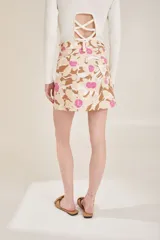 Falda corta con estampado psicodélico en tonos beige y rosa, con cintura alta y botones frontales.