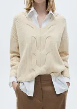 Sweater color crema de tejido de punto grueso con diseño trenzado, cuello en V y corte recto.