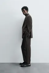 Pantalón de vestir negro de lana, corte recto, con bolsillos laterales y traseros de ojal con botón.