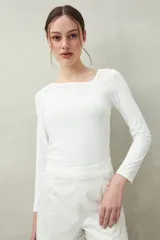 Top blanco de manga larga con escote asimétrico.