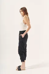 Pantalón jogger negro de nylon con elástico ancho en la cintura, puños elásticos ajustables y lazos laterales para fruncir.