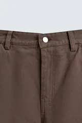 Pantalón negro de corte amplio, confeccionado en tejido de algodón con efecto lavado. Presenta bolsillos frontales, traseros de parche, tira multifunción y bolsillos laterales en las perneras. Cuenta con cierre frontal con cremallera y botón.