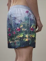 Short de baño verde con estampado de margaritas blancas y cordón ajustable naranja.