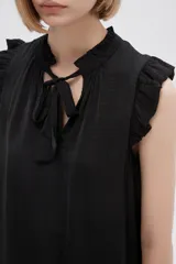 Blusa sin mangas color crudo con cuello con lazo y volados en los hombros.