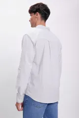 Camisa de hombre de corte clásico, confeccionada en tela Oxford con rayas verticales grises y blancas. Tiene cuello abotonado, manga larga con puños abotonados y un bolsillo en el pecho.