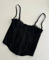 Corset negro de encaje con copas preformadas, breteles finos regulables y ballenas de soporte.