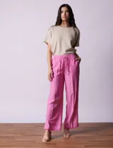 Pantalón ancho de lino color fucsia, marca Zac & Rachel. Tiene pretina elastizada con lazo de ajuste, bolsillos delanteros y ruedo con tajo y flecos.