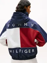 Campera náutica amplia reversible de nailon, con diseño color block en rojo, blanco y azul marino. Tiene capucha fija, cierre de cremallera oculto con botones a presión, puños y bajo elásticos, dos bolsillos ribeteados en la cintura, parche con logo de Tommy Hilfiger en el pecho y logo de Tommy Hilfiger en el cuello, las mangas y la espalda.
