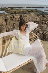 Bolso tipo tote tejido a crochet, con hilo 100% algodón, a rayas horizontales color crema y lila, con volados en los bordes y manijas reforzadas.