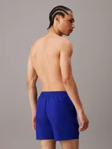 Short de baño azul con cintura elastizada y cordón blanco. Logo de Calvin Klein estampado en blanco en la pierna izquierda.