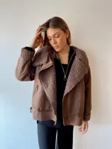 Campera marrón de gamuza sintética con cuello, puños y ruedo de piel sintética color marrón claro. Tiene cierre cruzado con cremallera y bolsillos laterales con cremallera.
