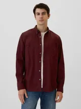 Camisa celeste a rayas verticales blancas, de corte clásico, con cuello abotonado y bolsillo en el pecho.