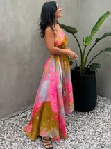 Vestido largo de tela fluida, color verde esmeralda con estampado abstracto en tonos turquesa y detalles dorados. Diseño asimétrico con un solo tirante tejido en el hombro.