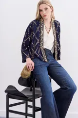 Kimono corto azul marino con estampado geométrico dorado, confeccionado en viscosa jacquard con lurex. Presenta guarda bordada en piedras y canutillos, y forrería interior.