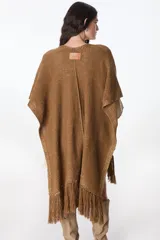 Ruana color beige de tejido de punto con flecos en el ruedo.