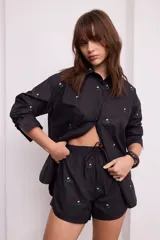 Short negro con bordado de flores rosas, con elástico en la cintura y cordón ajustable.