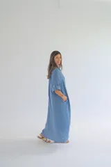 Vestido camisero largo color celeste, de corte amplio, con cuello camisero, abotonadura frontal y mangas largas con puños abotonados.