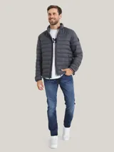 Chaqueta acolchada gris de poliamida con cuello alto, cierre de cremallera, dos bolsillos delanteros con cremallera y logo de Tommy Hilfiger bordado en el pecho.