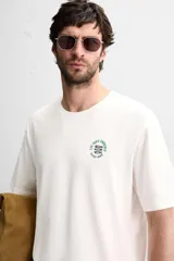 Camiseta blanca de corte holgado, cuello redondo y mangas cortas. Presenta un bordado y estampado combinado en el frente.