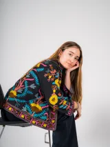 Chaqueta negra con bordado floral multicolor, de corte recto y mangas largas.