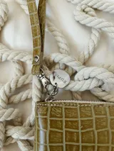 Billetera pequeña de cuero verde con textura tipo cocodrilo, forrada, con cierre metálico y pulsera para colgar de la muñeca.