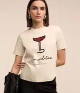 Remera de algodón color crema con cuello redondo y mangas cortas. Estampa frontal de una copa de Cosmopolitan y la inscripción "Cosmopolitan".