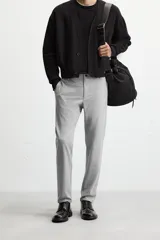 Pantalón negro de corte slim fit, confeccionado en tejido elástico. Cuenta con cintura elástica, bolsillos frontales y traseros de vivo. Cierre frontal con cremallera y botón.