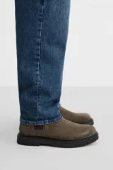 Bota Chelsea color marrón topo de cuero serraje, con elásticos laterales negros, tirador trasero y suela track.