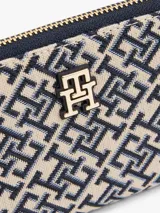 Billetera Tommy Hilfiger con cierre de cremallera, diseño integral de monogramas TH en jacquard azul y beige, dos compartimentos principales, múltiples ranuras interiores para tarjetas, bolsillo interior con cremallera e insignia del monograma TH en la parte delantera.