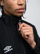 Campera deportiva Umbro de nylon con diseño color block en blanco, azul y rojo. Tiene cuello alto, cierre frontal con cremallera y bolsillos laterales. Logo de Umbro bordado en el pecho.