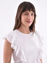 Remera blanca de cuello redondo con detalle de volados que nacen en los hombros y bajan por el frente.