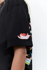 Remera negra de algodón con cuello redondo y estampado de cuatro estrellas de colores en el pecho.