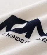 Remera de manga corta con cuello polo contrastante en azul marino y abertura en V. El cuerpo de la prenda es color crema y lleva un estampado frontal con la palabra "WONDER".