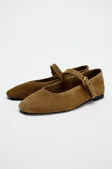 Zapato plano tipo bailarina color marrón de serraje, con escote redondo y cierre mediante hebilla en el empeine.