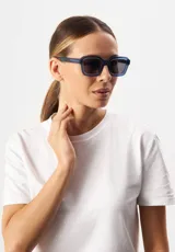 Lentes de sol Eco Shades modelo Romano con montura cuadrada azul traslúcido y lentes grises. Fabricados con acetato biodegradable y lentes de PMMA reciclado.