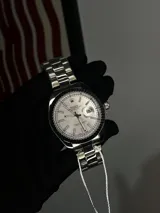 Reloj Rolex Datejust réplica AA+, con malla de acero inoxidable, esfera plateada con indicador de fecha y cristal con lupa sobre el fechador.