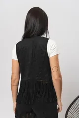 Chaleco negro de gamuza sintética con flecos y tachas plateadas.