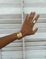 Brazalete ancho de bronce macizo con textura irregular.