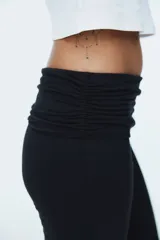 Pantalón de yoga negro de microfibra suave, con cintura alta de doble capa, costuras laterales fruncidas y piernas acampanadas.