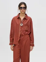 Pantalón de vestir color ladrillo, de corte holgado y tiro alto, con caída recta y detalle de diseño al costado.