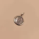 Medalla redonda de plata 925 con la figura en relieve de San Expedito, representado con una túnica y sosteniendo una cruz y una espada. El borde es liso y tiene una argolla para colgar.