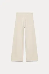 Pantalón de jean de tiro alto color negro con pierna ancha, bolsillos delanteros y traseros, y cierre frontal con cremallera y botón metálico.