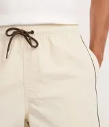 Bermuda deportiva masculina color marrón, con cintura elástica y cordón ajustable. Presenta piping contrastante en blanco a lo largo de los bordes y bolsillos funcionales. Confeccionada en poliamida de secado rápido.