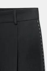 Pantalón negro de tiro medio con trabillas, falso bolsillo de vivo en espalda, detalle de pespuntes combinados a contraste y pinzas. Cierre frontal con cremallera y botón.