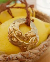 Collar con cordón naranja y dije de flor dorada.