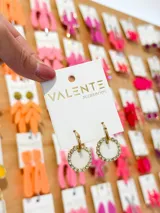 Aros colgantes dorados con forma de argolla, con dije circular blanco con borde de strass.