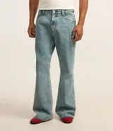 Pantalón de jean celeste con lavado dirty, corte flare, cintura fija con trabillas, cierre con botón y cremallera, y bolsillos.