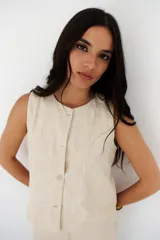 Top color crema con bordado floral, sin mangas, con cuello redondo y cierre frontal con botones.