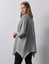 Camisa celeste de tencel, corte amplio, con cuello mao, escote en V y abotonadura frontal. Tiene bolsillos aplicados en el pecho, mangas 3/4 regulables con presilla y ruedo desflecado.