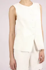 Chaleco negro sin mangas, con cuello redondo y cierre frontal de botones. Presenta detalles de encaje o apliques en los laterales y un corte ligeramente holgado.